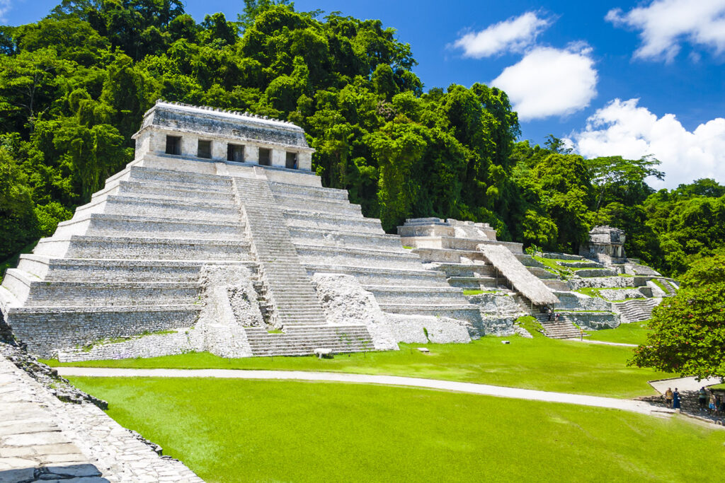 A captivating image of Palenque, featuring ancient Mayan ruins nestled in the lush jungle, with towering pyramids and intricate stone carvings that reveal the rich history and mystique of this archaeological wonder.