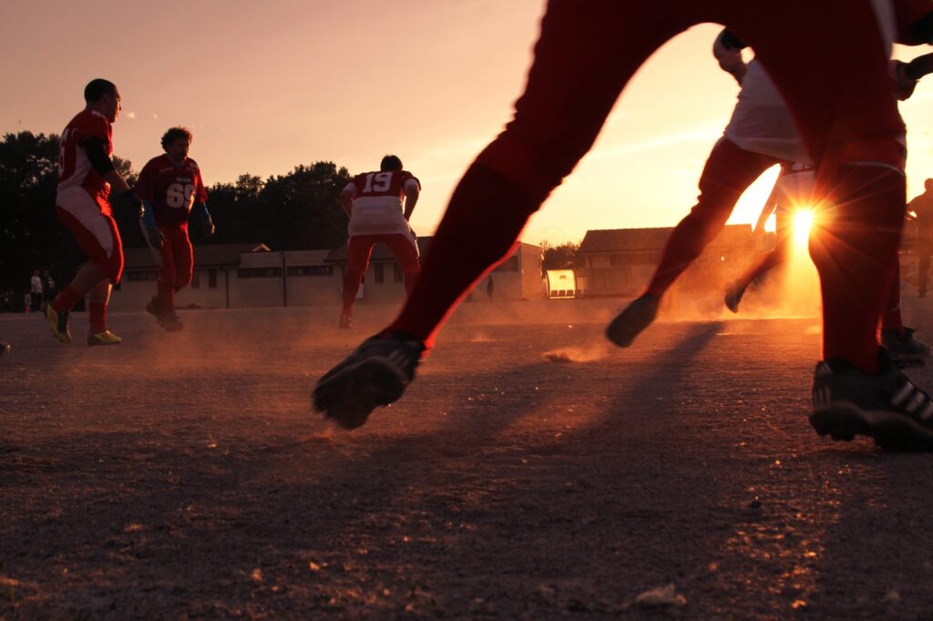 A group of friends playing soccer in the evening, enjoying a fun and energetic match under the warm glow of the setting sun.